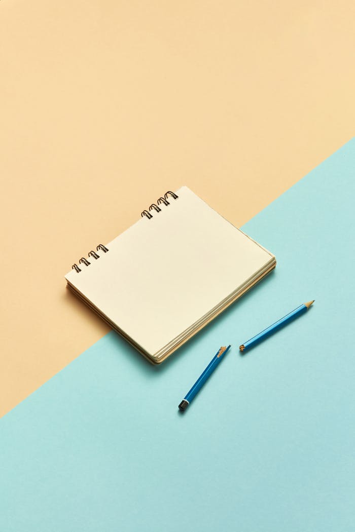 Empty notebook with two blue pencils on a pastel split background - perfect for mockups.
